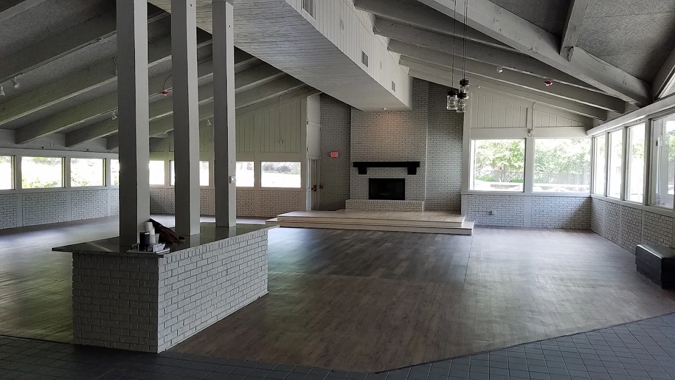 The main event room at The Little Cottage, with painted white brick, vaulted wood ceilings, and reception seating