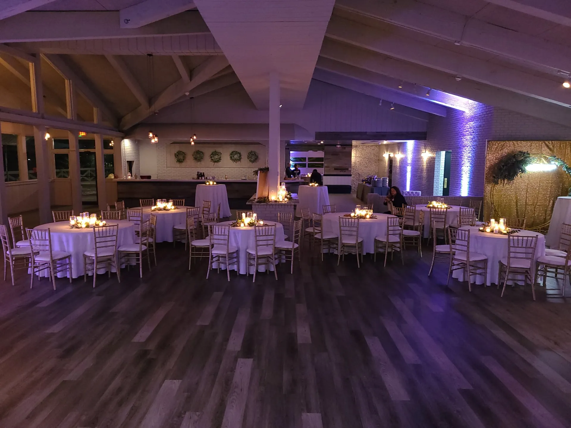 The light-filled main event room at The Little Cottage in Smyrna, GA, with vaulted wood ceilings, painted white brick, and cocktail tables set for a reception